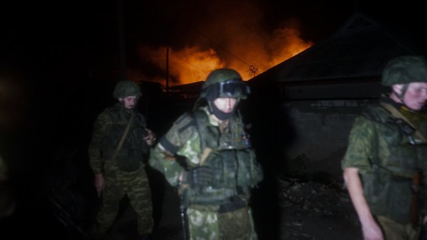 Russia-backed rebels pass by a burning house destroyed by night-long shelling in Donetsk, eastern Ukraine, on Sunday.