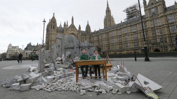Two children whose school was bombed in Aleppo pose for pictures in a mock destroyed classroom outside the Houses of Parliament in London last week. 