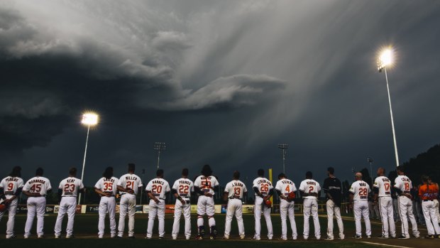 Canberra Cavalry players line up during a moment of respite from the supercell storm in Canberra on Saturday.