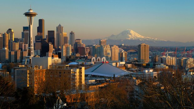 The Seattle city skyline at sunset with the Space Needle, downtown and Mount Rainier from Queen Anne Hill.