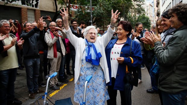 An elderly lady is applauded as she celebrates after voting at a school assigned to be a polling station by the Catalan government in the Gracia neighbourhood of Barcelona.