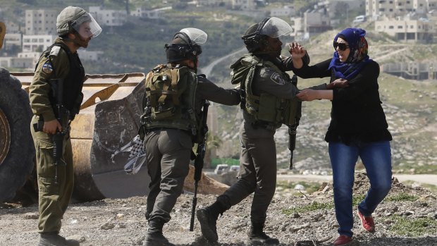 A Palestinian woman scuffles with Israeli border policemen as they clear a protest on land that Palestinians said was confiscated by Israel for Jewish settlements, near the occupied West Bank town of Abu Dis, during election day.