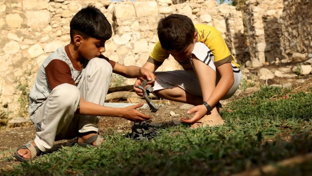 Boys hold pieces of metals from a crater caused by a Turkish air strike against Kurdistan Workers Party (PKK) camps.