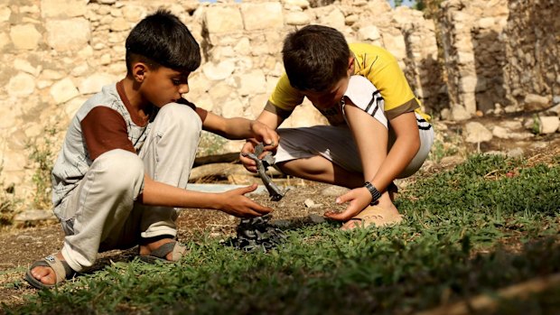 Boys hold pieces of metals from a crater caused by a Turkish air strike against Kurdistan Workers Party (PKK) camps.