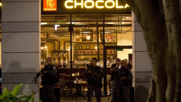 Israeli police officers stand guard at the scene of a shooting attack, outside a Max Brenner cafe, in Tel Aviv.