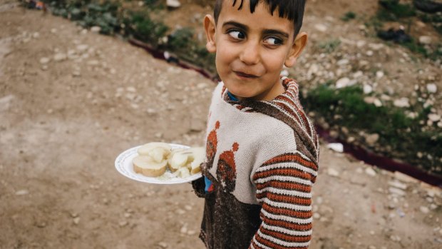 A Syrian boy walks in Kawergosk refugee camp in northern Iraq carrying a plate with boiled potatoes. 