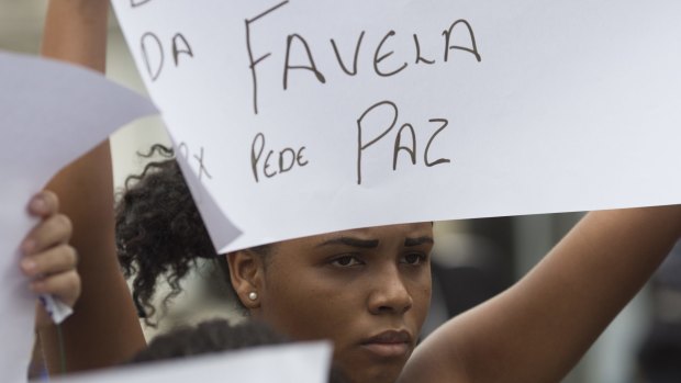A woman holds a sign that reads in Portuguese "Favela asks for peace" during the burial of Roseli Jesus on Tuesday.