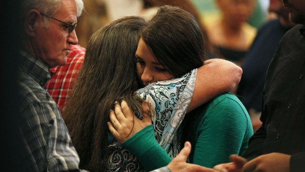 Lacey Scroggins, right, embraces a  woman at a church service in Roseburg on Sunday. 