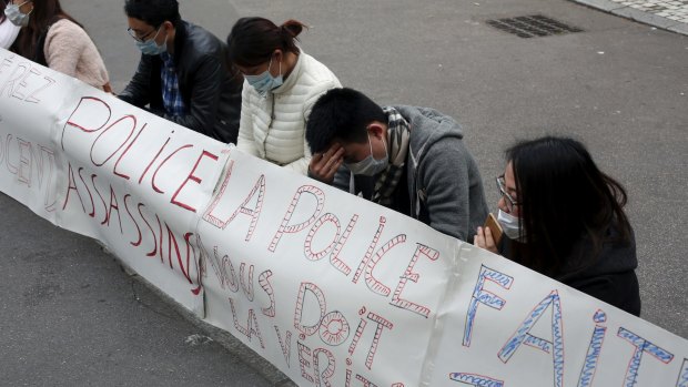 Chinese immigrants sit behind a banner reading on the left "police murderers" and in the centre "police owes us the truth" during a protest in Paris on Tuesday.