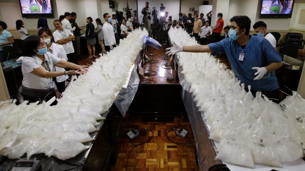 A man passes a box of rubber gloves after they arranged packs of seized methamphetamine at the National Bureau of Investigation in Manila, Philippines on Monday. 