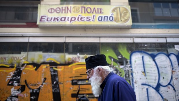 A priest walks past a closed shop in downtown Athens: many Greeks are hoping the imminent election will set the nation back on the track to economic growth.
