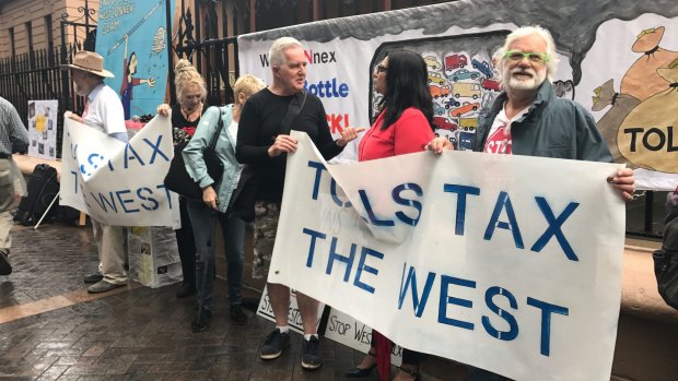 Protesters hold signs during a rally against the WestConnex road project outside the NSW parliament building in Sydney.