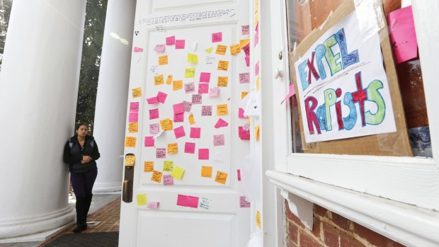 A University of Virginia student looks over postings on the door of Peabody Hall related to the Phi Kappa Psi gang rape allegations.