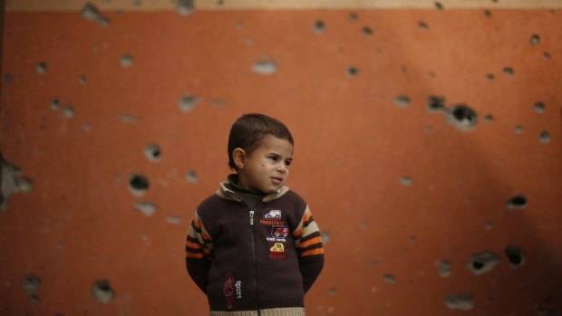 A Palestinian boy stands outside a mosque witnesses said was damaged by Israeli shelling.