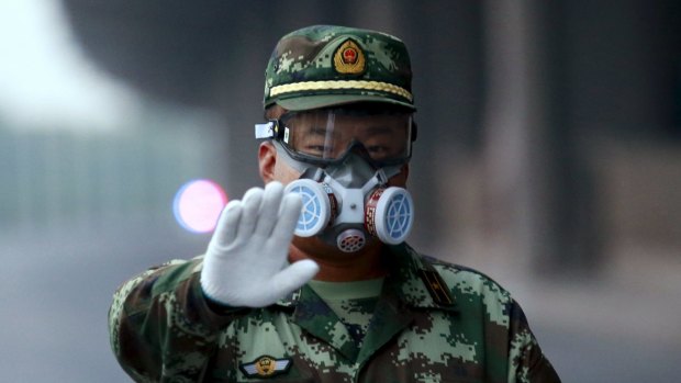A paramilitary policeman wearing a mask gestures to the photographer to stop as he blocks a road leading to the evacuated residential area and explosion site, at Binhai new district in Tianjin, China.