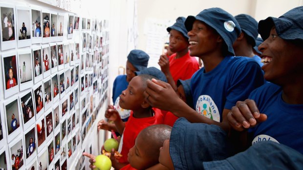 Children look at their instant photographs they have taken throughout a week at a community camp at the new Mamohato Children's Centre, in Maseru, Lesotho. 