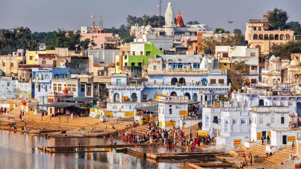 Pushkar's white cubist buildings cram the lake's edge and are framed by barren brown hills.