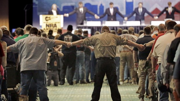 National Rifle Association members hold hands during the opening prayer at the annual meeting of members at the NRA convention on April 11 in Nashville, Tennessee. 