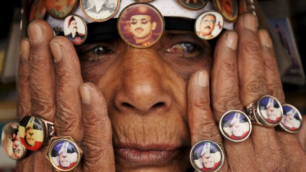 A woman supporting former dictator Ali Abdullah Saleh wears rings and badges showing Saleh and his son Ahmed Ali Saleh (in sunglasses, above her nose)  during a rally in the Yemeni capital Sanaa.