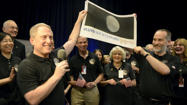 NASA principal investigator for the New Horizons mission Alan Stern (left) and co-investigator Will Grundy (right) hold up a copy of a US postage stamp depicting an outdated image of Pluto.