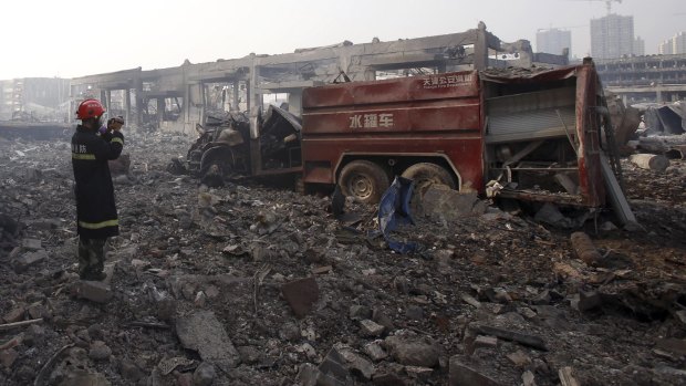 A firefighter inspects a destroyed fire truck at the site of an explosion in Tianjin.