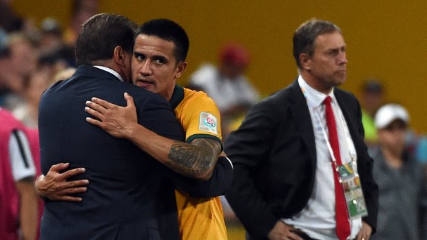 Job done ... Australia's Tim Cahill hugs coach Ange Postecoglou (left) as China's coach Alain Perrin (R) looks on at the game as it slips away from China. 