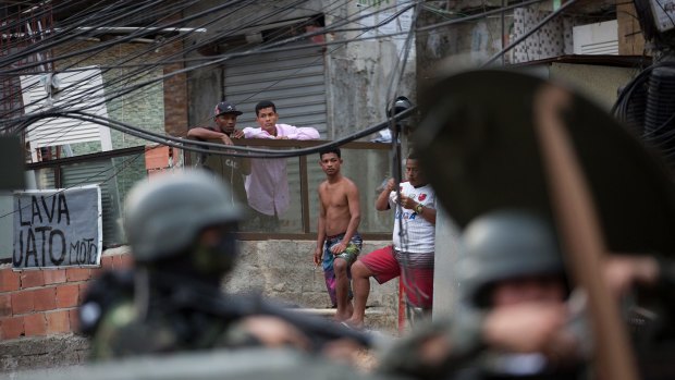 Residents look at an armoured vehicle patroling the Rocinha favela, in Rio.