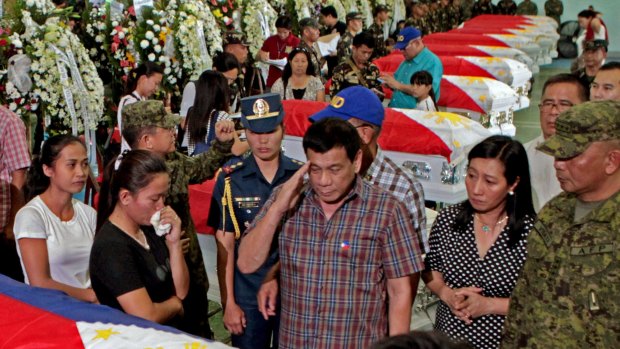 Rodrigo Duterte, front centre, salutes the flag-draped coffins of 15 soldiers killed in a gunbattle with Muslim Abu Sayyaf militants on Monday.