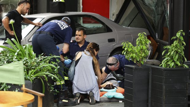 Paramedics work to stabilise a woman after she was run over outside Vinyl Cafe on Perkins Street in Newcastle on Friday.