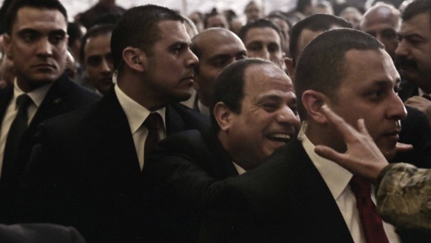 People try to shake hands with Egyptian President Abdel-Fattah el-Sissi, centre, during Christmas Eve Mass in Cairo.