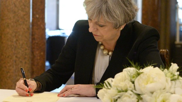 British PM Theresa May writes a message to the people of Manchester at Manchester Town Hall on Tuesday.