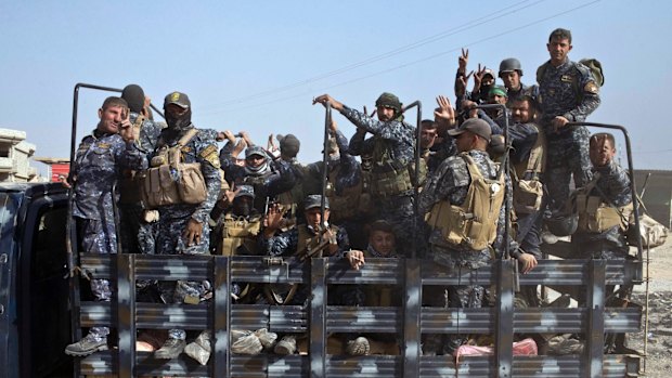 Iraqi National Police officers are transported on the back of a truck on the outskirts of Qayyarah, near Mosul.