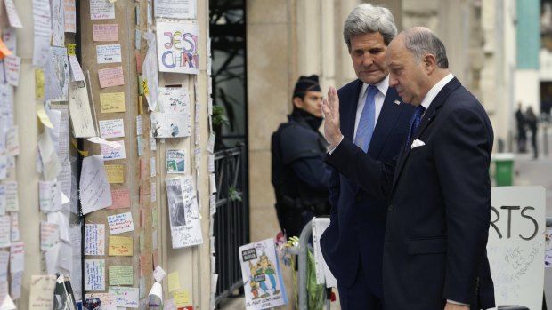 John Kerry (left) and French Foreign Minister Laurent Fabius at a memorial at the <i>Charlie Hebdo</i> newspaper office in Paris on Friday.