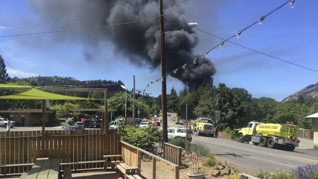 A train towing cars full of oil sends up a plume of smoke after derailing near Mosier, Oregon. 