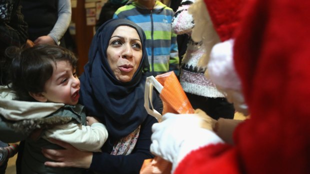 Syrian refugee Ola Hussain apologises to a volunteer dressed as Santa Claus as her one-year-old son Mohamed cries out in fear at a migrant shelter in Berlin.