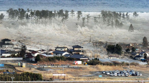 Waves from the tsunami hit residences after a powerful earthquake in Natori, Miyagi prefecture, in March 2011.