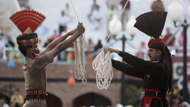 An Indian Border Security Force soldier, left, and a Pakistani Rangers soldier hold ropes to lower their respective flags in a daily ceremony. 