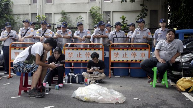 Police officers stand guard as students participate in a protest at the entrance to the Ministry of Education in Taipei on Friday.