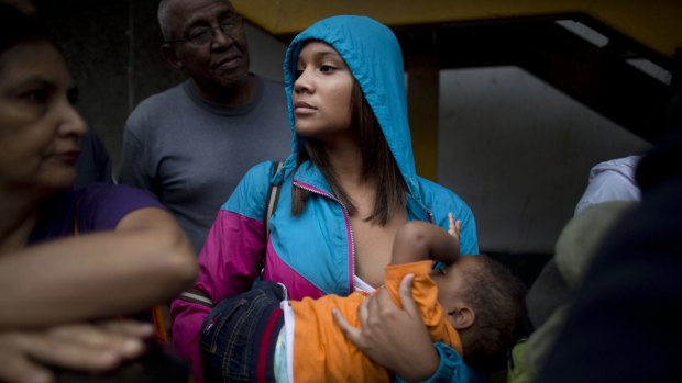 Madeley Vasquez, 16, breast feeds her one-year-old son Joangel as she waits in line outside a supermarket to buy food in Caracas, Venezuela. 