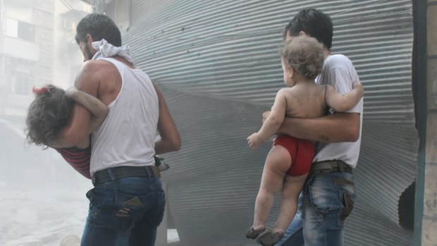 Syrians carry their children after the Syrian army carried out air strikes in Aleppo, Syria on August 13.
