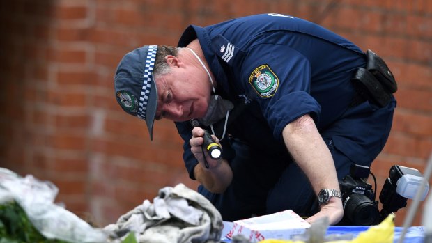 A police officer searches items from a property in Lakemba as part of an investigation into an alleged terrorism plot.