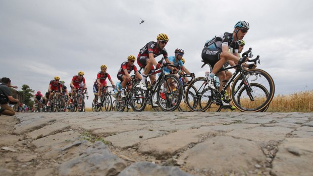 Stage winner Germany's Tony Martin, right, and the pack ride over a cobblestone sector during the  223.5-kilometre fourth stage of the Tour de France which finished in Cambrai, France.
