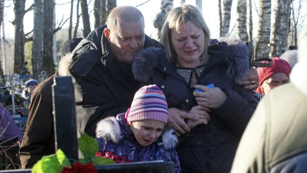 Grieving: Pavel, the nephew of one of the plane crash victims Nina Lushchenko, left,  reacts at her grave side with her daughter Veronika, right, and granddaughter, during her funeral at a cemetery in the village of Sitnya in Russia.