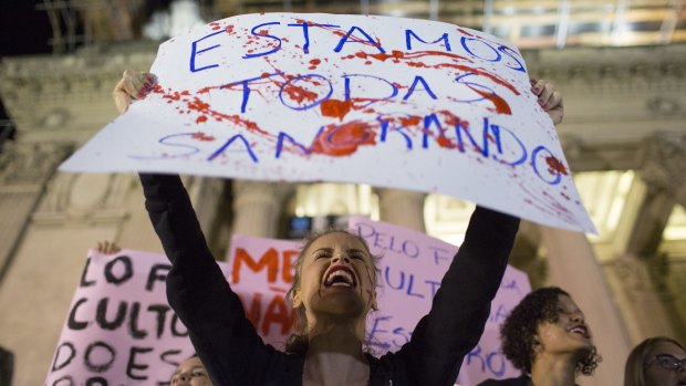 A woman shouts holding a banner that reads in Portuguese "We're all bleeding" in a protest sparked by the shocking rape case. 