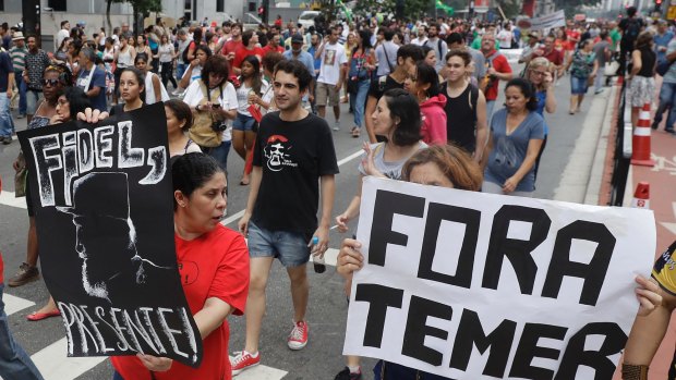 Demonstrators march with a sign that says in Portuguese "Get out Temer" and a drawing of Cuba's late President Fidel Castro in Sao Paulo on Sunday.