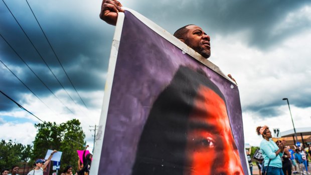 John Thompson carries a large photo of his friend Philando Castile during a demonstration on Sunday.
