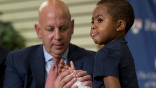 As Dr. L. Scott Levin holds his hand, double-hand transplant recipient eight-year-old Zion Harvey moves his fingers.
