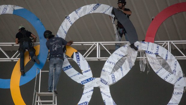 Workmen install a set of Olympic rings on the outside of an Olympic Park venue, in Rio.