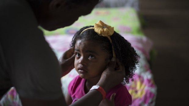 Sandra Maria adjusts her daughter's hair band at a hotel housing people displaced by the Samarco dam failure, in Mariana, Minas Gerais, Brazil.