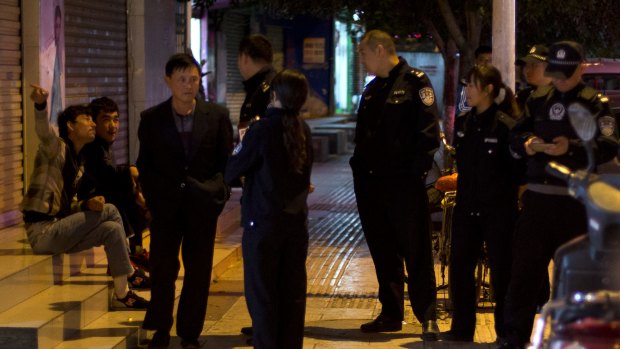 Police officers question two Uighur men, left, as a Han Chinese man walks past them in Kunming, in western China's Yunnan province in 2014. 